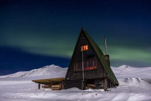 Skátaskálinn Þristur í snjó undir norðurljósum.