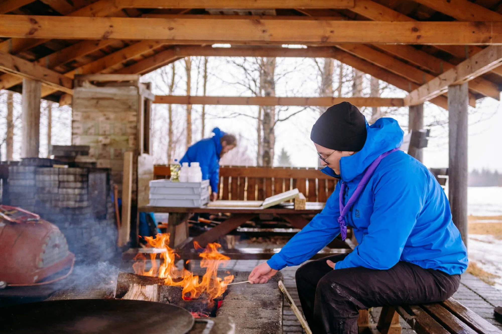 Vættaskáti grillar við varðeld í skýli úti í skógi.